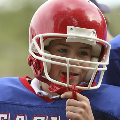 A teenager playing football while protecting his teeth with Mouthguards