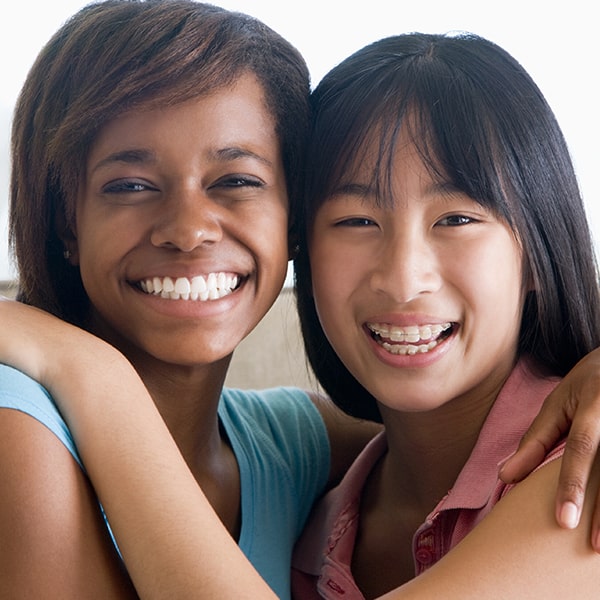 Two young women hugging while one of her has braces on