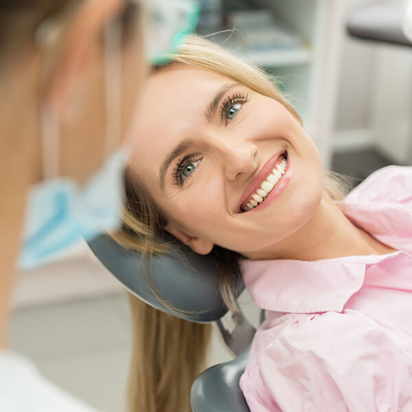 A patient sits in a dentist’s chair and smiles.